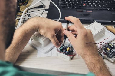 Elektronik cihazların tamiri, kalay lehimleme parçaları. Tornavida tutan adamın elleri. Bilgisayar devre kartı.