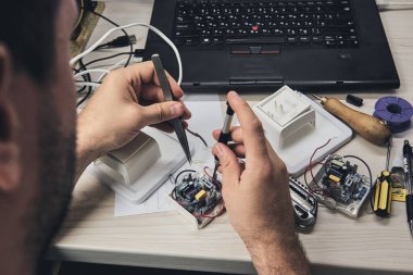 Elektronik cihazların tamiri, kalay lehimleme parçaları. Tornavida tutan adamın elleri. Bilgisayar devre kartı.