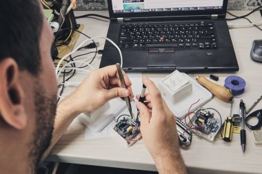 Elektronik cihazların tamiri, kalay lehimleme parçaları. Tornavida tutan adamın elleri. Bilgisayar devre kartı.