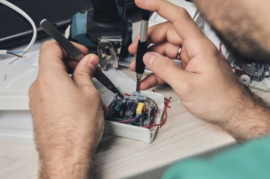 Elektronik cihazların tamiri, kalay lehimleme parçaları. Tornavida tutan adamın elleri. Bilgisayar devre kartı.