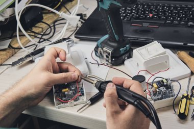Elektronik cihazların tamiri, kalay lehimleme parçaları. Tornavida tutan adamın elleri. Bilgisayar devre kartı.
