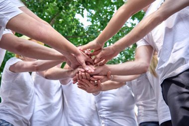 Kurumsal takım oluşturma partisinde bir grup insan. Eller üst üste, ortaklar dışarıda duruyor..