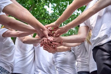 Kurumsal takım oluşturma partisinde bir grup insan. Eller üst üste, ortaklar dışarıda duruyor..