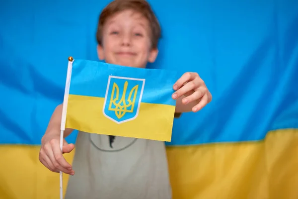 男孩手握乌克兰国旗 背景黄蓝相间 孩子们表现出爱心来支持乌克兰 乌克兰危机 俄罗斯侵略乌克兰 俄罗斯对乌克兰的战争 — 图库照片