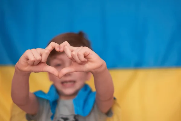 Menino segurando em mãos bandeira amarelo-azul ucraniana. Crianças apoiar a Ucrânia, mostrando o coração — Fotografia de Stock