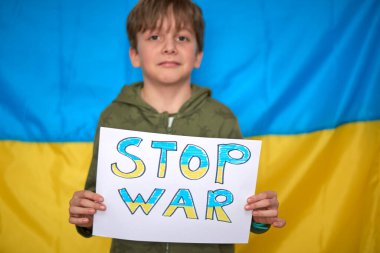 Çocuk elleri Ukrayna bayrağının arkasına sarı-mavi pankart asmış. Çocuklar Ukrayna 'yı destekliyor, savaşı durduruyor, Ukrayna hashtag' inde kalıyor.