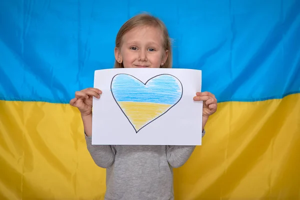 Mãos de menina segurando bandeira com coração amarelo-azul desenhado na bandeira ucraniana. Parem a guerra, fiquem com a Ucrânia. — Fotografia de Stock