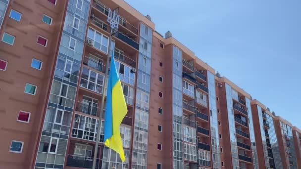 Die ukrainische gelb-blaue Flagge flattert im Wind an einem Fahnenmast mit einem nationalen Dreizack — Stockvideo