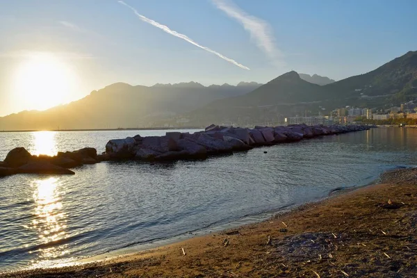 Gün batımında bulutlu bir günde gölün küçük bir sahili.