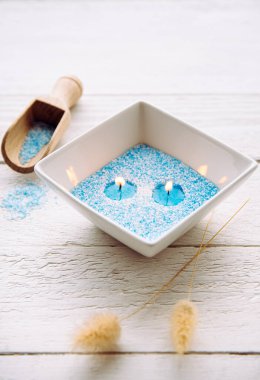 Mavi ve beyaz granüle balmumu kristalleri kâseye doldurup fitil yerleştirmek için. Ahşap zemin üzerinde beyaz seramik kasede el yapımı kum mumu, mum tozlu kaşık..