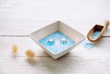 Mavi ve beyaz granüle balmumu kristalleri kâseye doldurup fitil yerleştirmek için. Ahşap zemin üzerinde beyaz seramik kasede el yapımı kum mumu, mum tozlu kaşık..