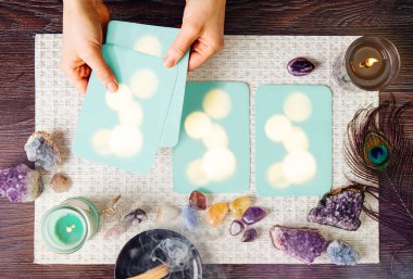 Beyaz arka planda, yarı değerli taş kristalleri ve yanan mumlarla çevrili ev yapımı kehanet kartları olan güverte. Ametist kristal melek heykelciğine odaklan.