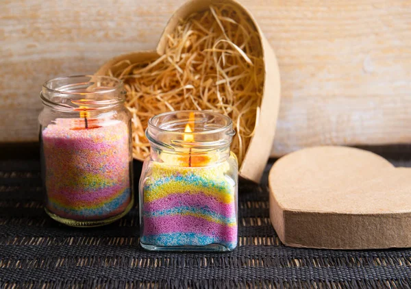 Children made fun colorful layered wax powder candles in home by pouring powder in old baby food jar and inserting wick inside. Hobby concept.