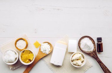 Making homemade deodorant stick with all natural ingredients concept. White wood background. Ingredients: arrowroot powder, baking soda, beeswax, shea butter, essential oil, cornstarch, coconut oil.