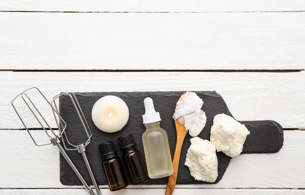 Making bodywhip also known as body butter, skin care moisturizer cream. Ingredients on white wooden background: shea butter,solid coconut oil, sweet almond oil and essential oils. Lot of copy space.