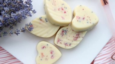 Küçük kalp ve yaprak şekilli banyo mantarları, banyo bombasının tereyağlı versiyonu beyaz tepside mum yanıyordu. Ev spa konsepti.