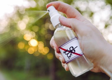 Kadın el ele tutuşmasını ve DIY ev yapımı yağ bazlı sivrisinek kovucuyu akşamları ormanın içinde kullanmasını yakından izleyin..