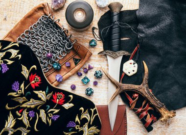 Fantezi rol yapma oyunu hala hayat konsepti. Çeşitli karakter nesneleri araçlarıyla dekore edilmiş arka plan. Hançer, zincir maili, tılsım, giysi, zar seti: D10, D20, D12, D6, D8.