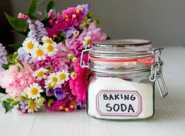 Adding baking soda powder inside cut flowers vase so cut flowers last longer fresh. Baking soda home use concept.