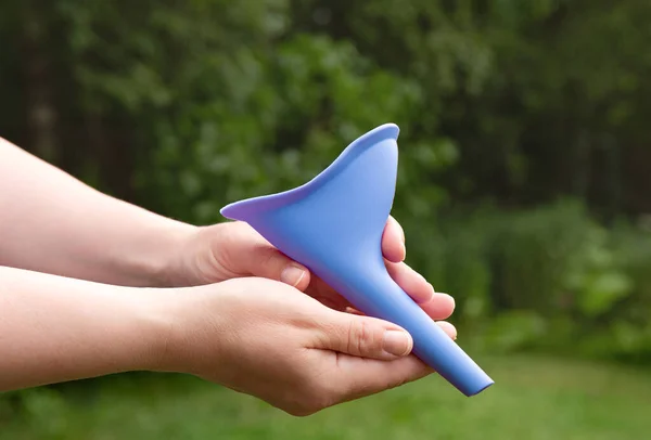 Device for women, pee funnel, to use while camping outdoors, helps urinating standing. Woman hands holding the tool.