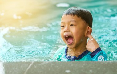 Çocuk yüzme havuzunda oynuyor yazın neşe ve neşe içinde gülümseyip eğleniyor.