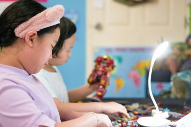 Çocuklar odada plastik blok oyuncağı oynuyorlar.