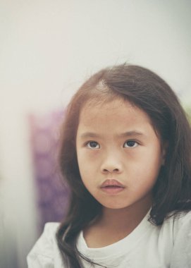 Küçük kız endişeli yüz ifadesine bakıyor.