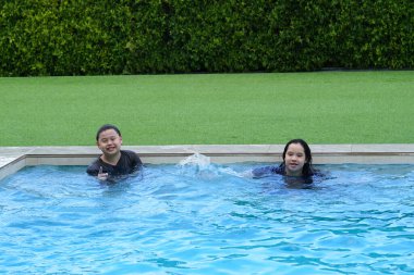 Çocuklar yüzme havuzunda mutlu gülümser.