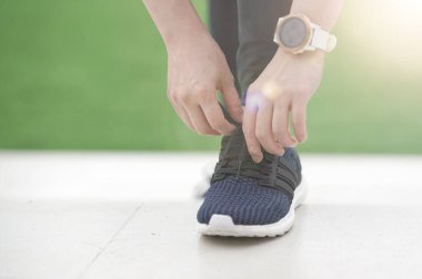Koşu ayakkabısı bağlayan kadın koşucu