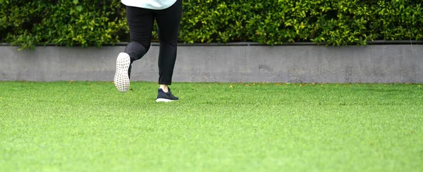 woman wear sport suit and running shoes runs on lawn selective focus with motion blur