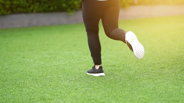 woman wear sport suit and running shoes runs on lawn selective focus with motion blur