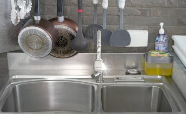 The sink faucet is at the sink in the kitchen.