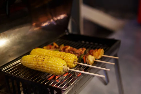 backyard party BBQ grilled. Roasted corn stick ,cooking at barbecue stove closeup.