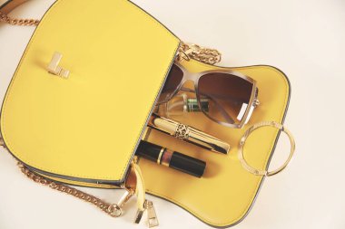 Kozmetik ürünler ve açık pembe deri kadın çantası.