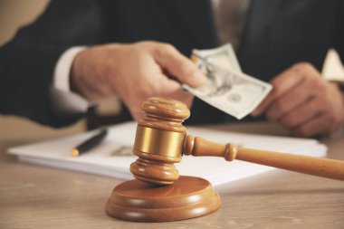 Adam gri arka planda takım elbisenin cebine para koyuyor.