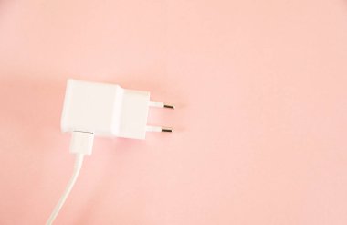 Pembe arka planda cep telefonu beyaz şarj cihazı