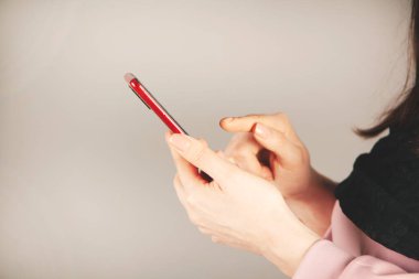 Gri arka planda akıllı telefonu tutan kadın.