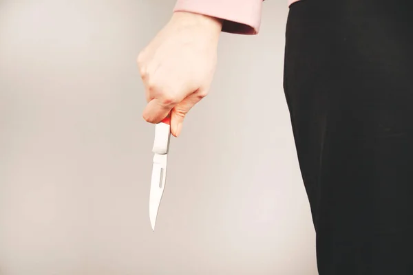 woman hand holding knife in back on gray background