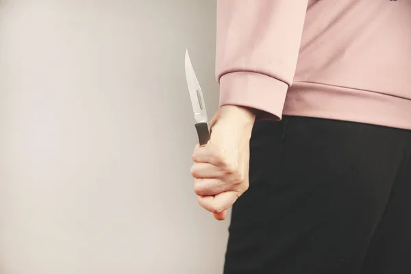 woman hand holding knife in back on gray background