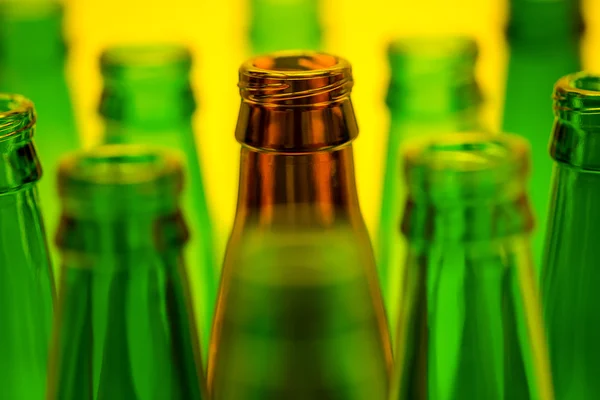 Ten empty beer bottles on a yellow background
