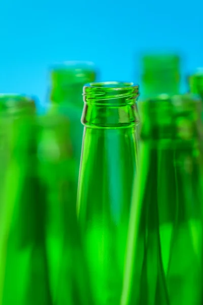 Seven green bottle necks on blue background