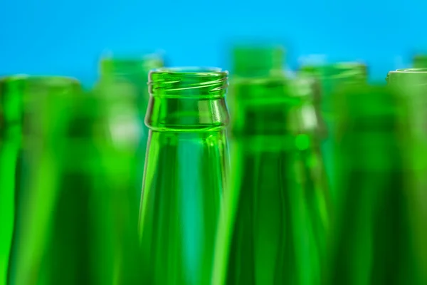 Nine green bottle necks on blue background
