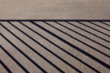 Asfalt zemin üzerine metal çit gölgesi