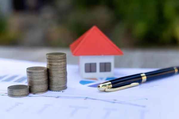 图表上的一堆硬币和橙色屋顶的房子计划储蓄的想法 用于购买房屋 抵押贷款和投资的想法 储蓄或投资于住房 — 图库照片