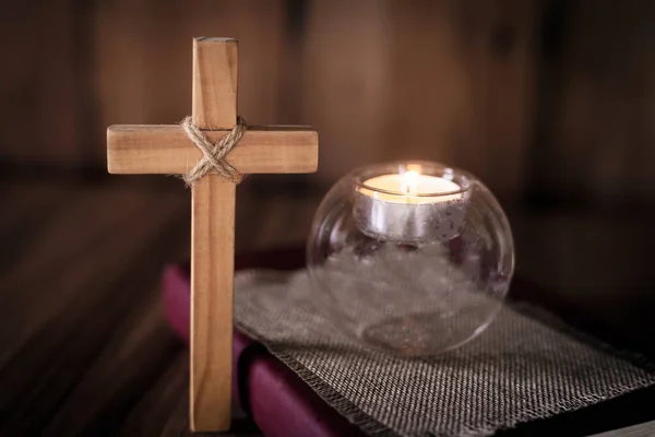 The cross and the light of the candle placed on the scriptures. Christian religious concepts The crucifixion of faith and faith in God. Faith, worship, Christian thinking.