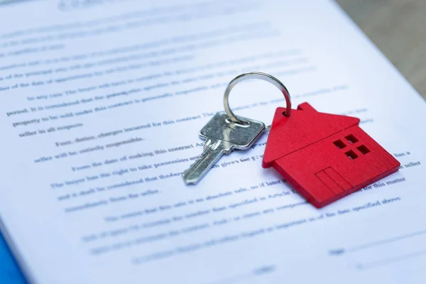 Key chain red house. The real estate agent is handing over the keys to the customer. Mortgage concepts. Rent, purchase and insurance for homes.