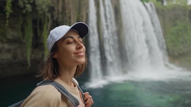 Портрет счастливой молодой женщины-туристки на огромном фоне Верхнего Дуденского водопада в Анталии. Знаменитая точка зрения и туристическое место в Турции. — стоковое видео