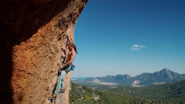 Athletisch attraktiver Mann Felskletterer trainiert Klettern an senkrechten Klippen auf anspruchsvoller Route. Bergsteiger zieht Seil aus qwickdraw und senkt sich auf niedrigeren Punkt, um Schritte nach oben zu wiederholen — Stockvideo