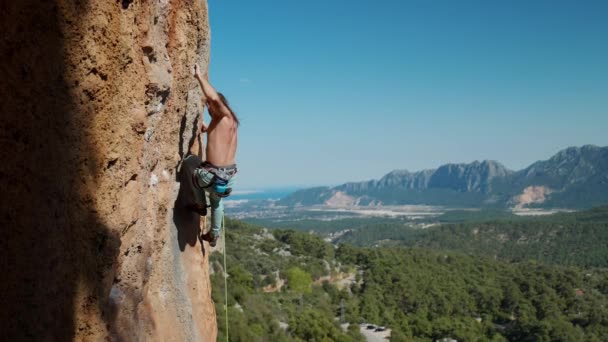 Hombre en forma escalando montaña arriba enfocándose en su próximo movimiento, alcanzando las presas de roca. cámara lenta cinematográfica, aptitud — Vídeos de Stock