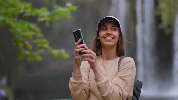 Close-up van mooie jonge glimlachende vrouw toerist nemen van foto of video op mobiele telefoon op waterval achtergrond in Antalya. Bezienswaardigheden van Beroemd uitkijkpunt en toeristische plaats in Turkije. — Stockvideo